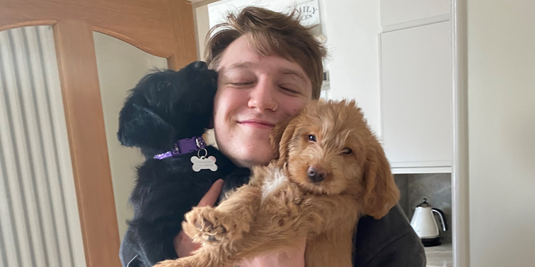 A student hugging two dogs.